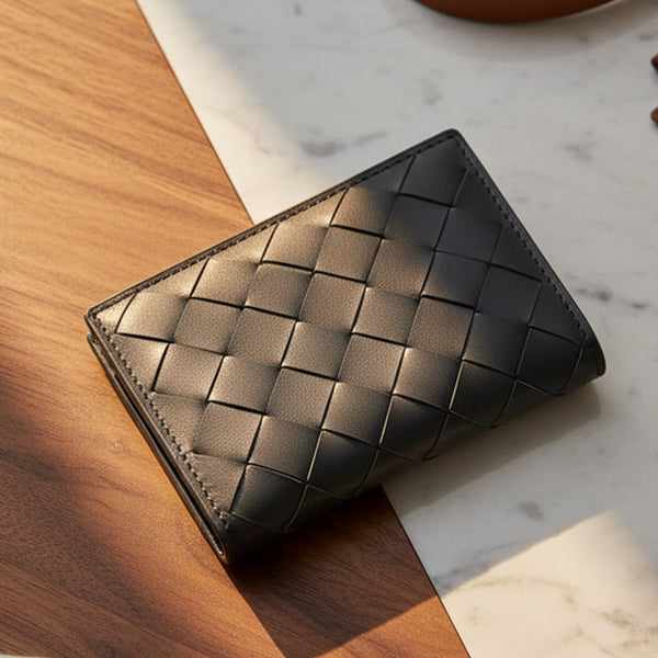 黑色手工編織皮革名片夾,斜角置於木紋與大理石背景,FREED 客製化刻字。