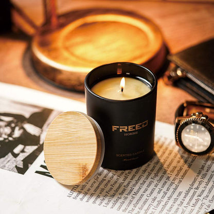 黑色玻璃罐身、淡黃色燭光，擺放於報紙旁，FREED客製化刻字。