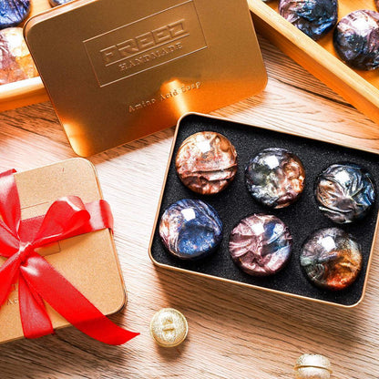 金屬禮盒裝著璀璨迷幻寶石手工皂，多種顏色，從上方俯視。FREED 客製化刻字。