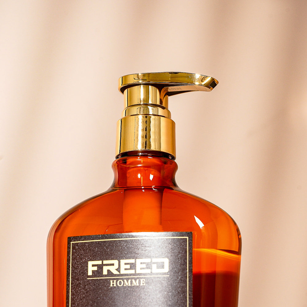 琥珀色玻璃瓶身，金色壓頭，背景柔和光影。FREED 客製化刻字。