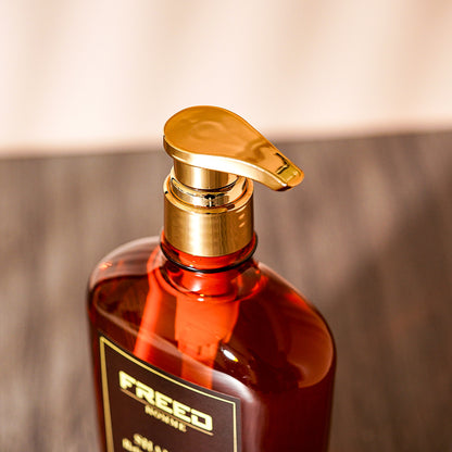 琥珀色瓶身，金色泵頭，特寫角度，FREED 客製化刻字。
