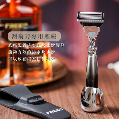 銀色刮鬍刀立於金屬底座，旁有黑色刀套。FREED 客製化刻字
