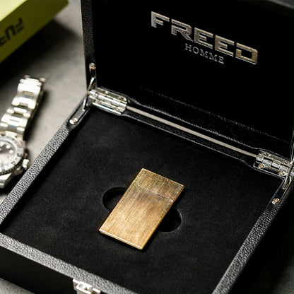 金色拉絲銅殼打火機，俯視角度，置於黑色盒內。FREED 客製化刻字。